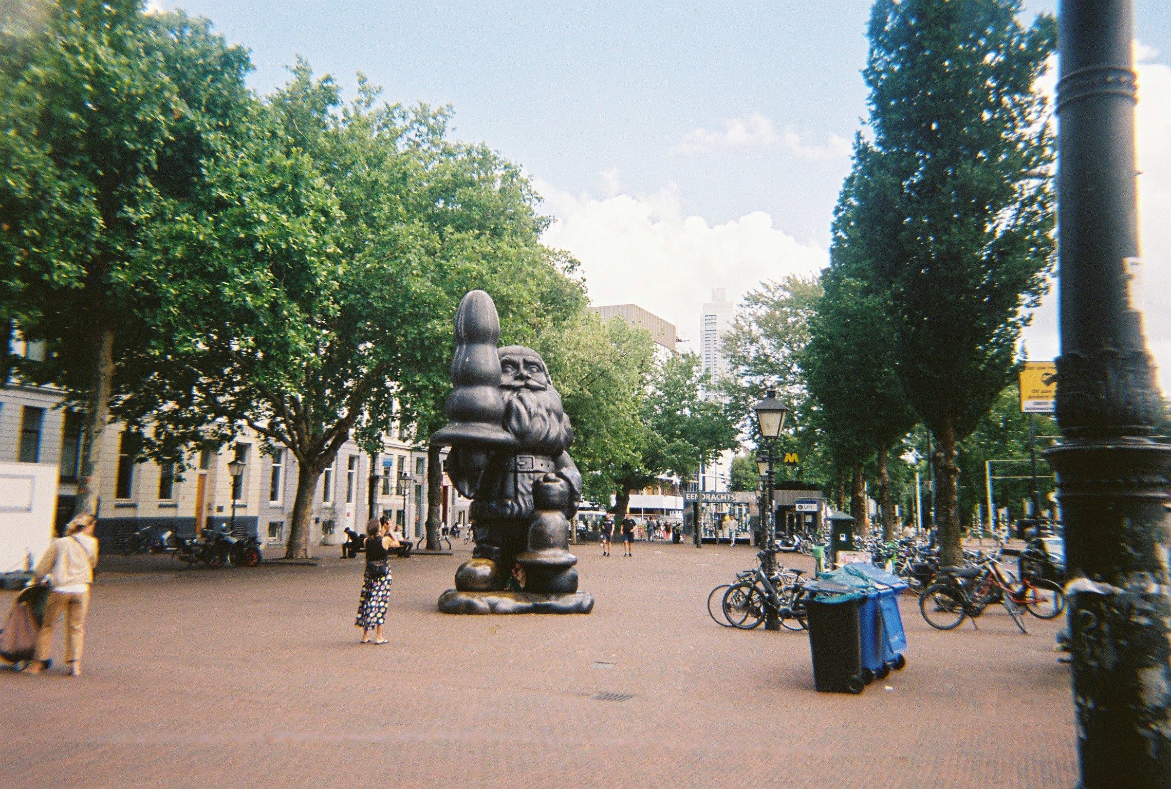 Large bronze gnome statue in Rotterdam public square with bicycles